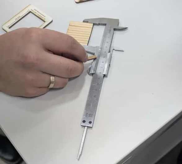 All ten laser-cut wooden pieces aligned and measured together to show total kerf loss.