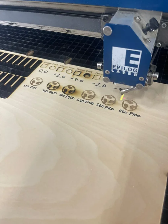 Wooden board showing results of different speed and power laser test cuts.
